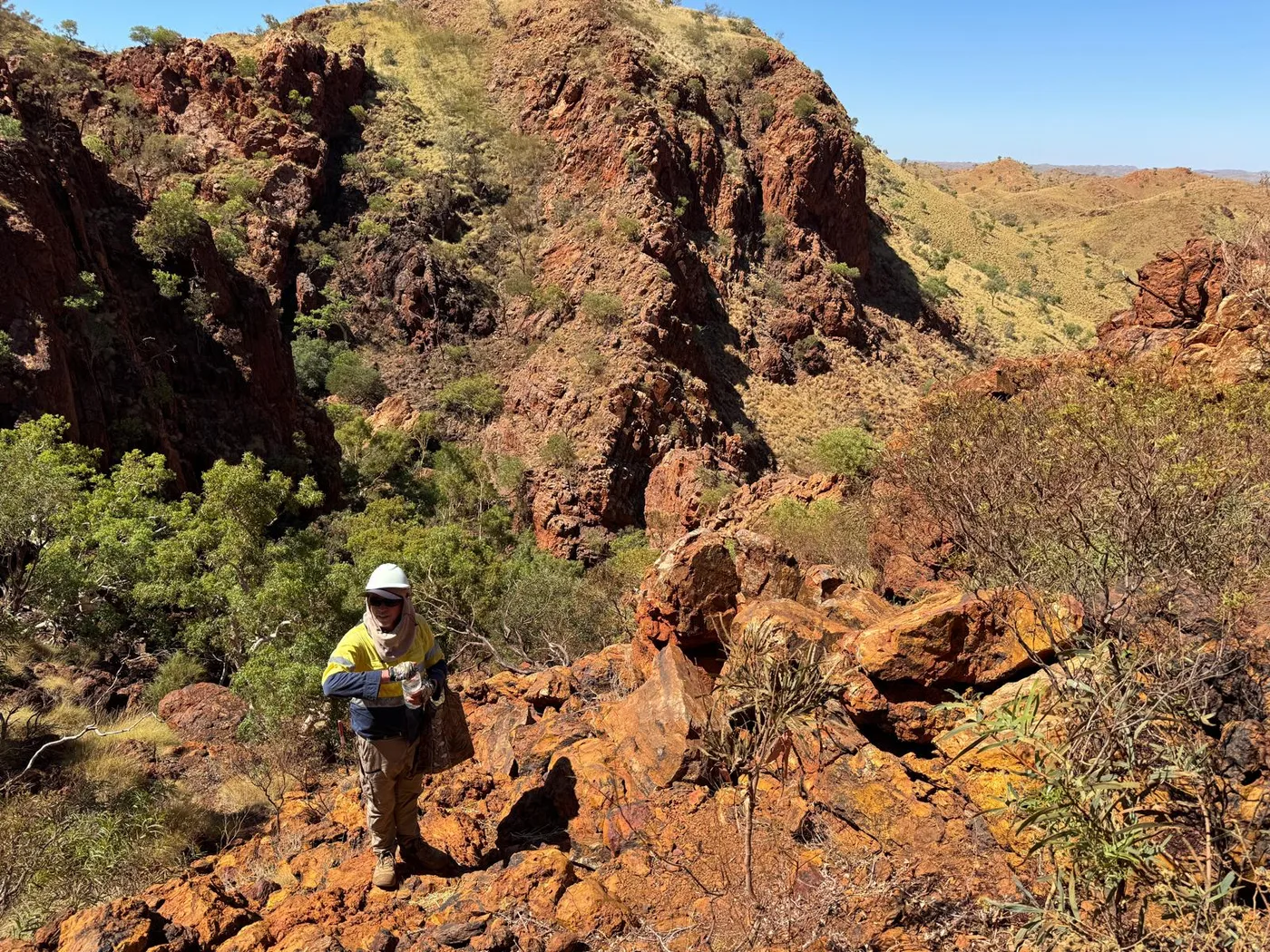 Supersensory engineer surveying a remote Pilbara site, with red rocky outcrops and arid scrub stretching to the horizon.
